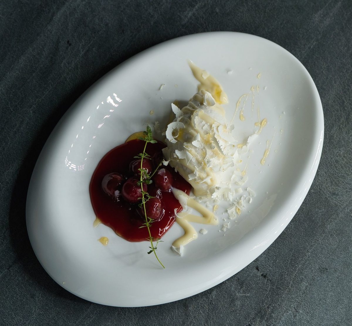 Süßer Gang mit Fruchtkompott und Creme, auf dunklem Schiefer