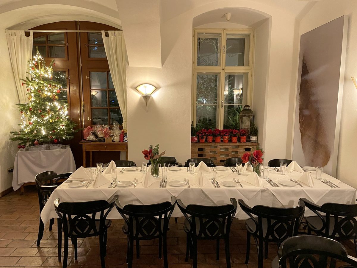 Weihnachtlich gedeckte Tafel im Gastraum, dahinter der geschmückte Christbaum
